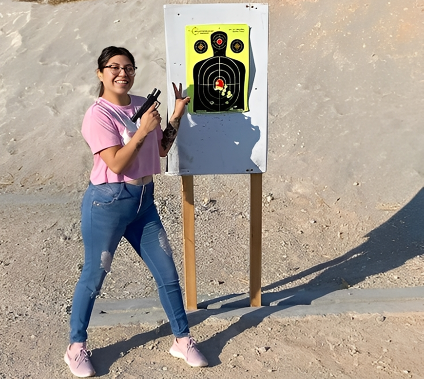 Person smiling with target at shooting range.